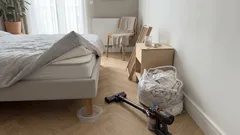 Ložnice s postelí, vysavačem a pytlem prádla při úklidu proti štěnicím