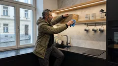 Muž čistí otevřenou polici v moderní kuchyni